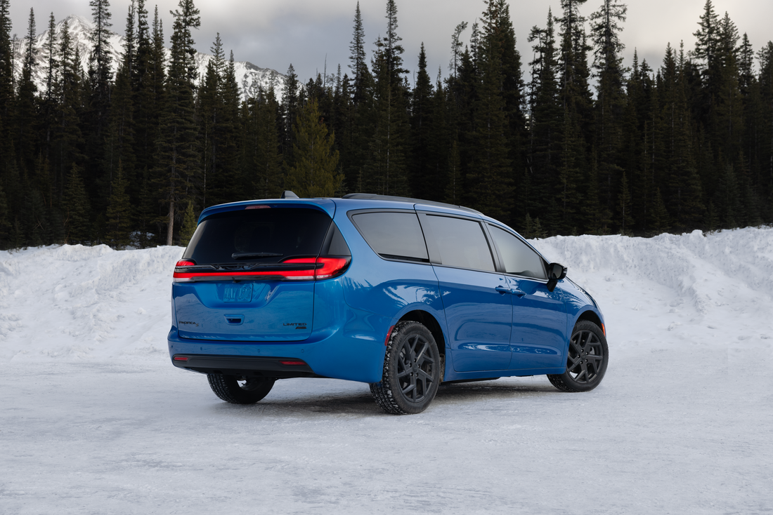 Blue 2027 Chrysler Pacifica Limited AWD S Appearance rear three-quarter view on snow showing full-width LED lightbar and 20-inch Foreshadow wheels