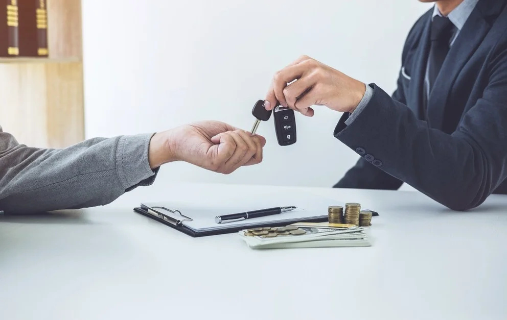 Customer trading vehicle keys across desk representing vehicle trade-in equity and appraisal in Wyoming
